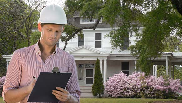 A home inspector in front of a house, going over the checklist.